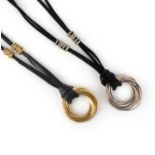 A gold pendant and silver pendant, each designed as interlocking hoops, one in gold, one in