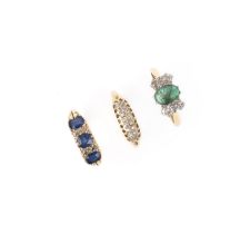 A collection of three gem-set rings, comprising: a ring set with a cabochon emerald between pairs of