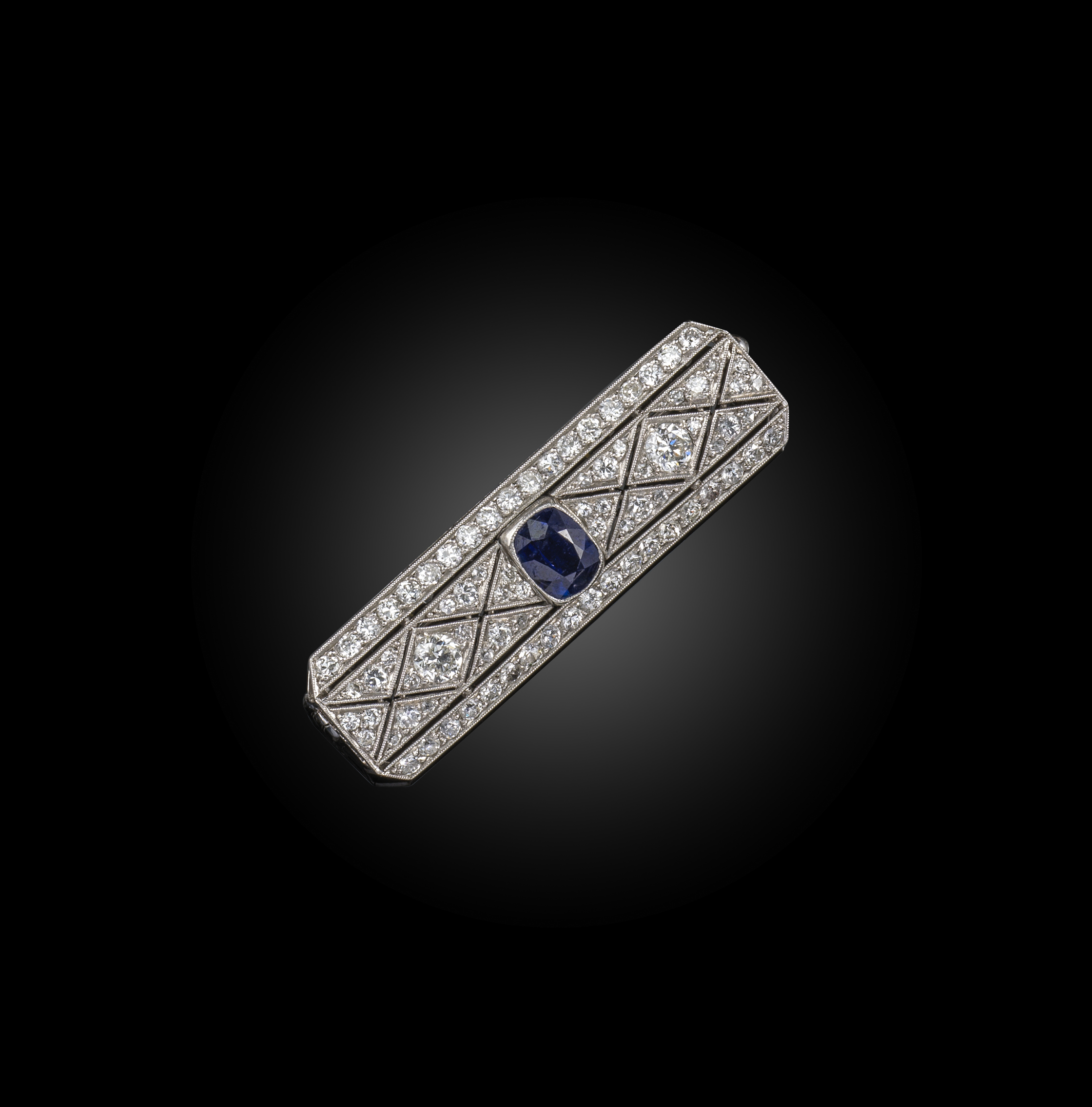 An early 20th century sapphire and diamond brooch, the cushion-shaped sapphire millegrain-set within