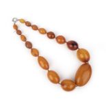 A single row amber bead necklace, composed of large graduated oval beads, the largest measuring