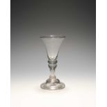 A small baluster wine glass, c.1730, with a bell bowl over a cushion knop and inverted baluster