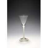 A wine glass, c.1750, with drawn trumpet bowl rising from a tapering opaque twist stem over a