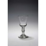 A rare composite baluster wine glass or goblet, c.1720, the generous bell bowl with a solid teared