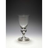 A heavy baluster glass, c.1710, the generous funnel bowl raised on a baluster stem enclosing a large