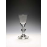 A large baluster wine glass, c.1710, the round funnel bowl with a solid base enclosing a single