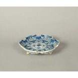 A Delft strainer dish or stand, 18th century, of hexafoil form, painted in blue with a formal