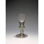 A small baluster glass, c.1710-20, the funnel bowl with a solid base, raised on a baluster stem with