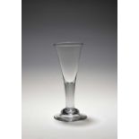 A tall wine glass, c.1750, the slender drawn trumpet bowl rising from a thick plain stem above a