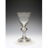 A rare baluster glass goblet, c.1715, the round funnel bowl finely engraved in diamond point with '