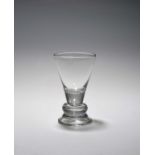 A firing glass, c.1730, the large flared funnel bowl with a solid base above a solid cushion knop