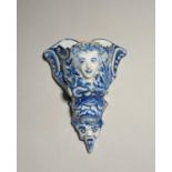 A delftware wall pocket, mid 18th century, moulded with a female mask to the top within leaf and
