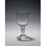 A large glass goblet, c.1740, the generous round funnel bowl raised on a thick plain stem