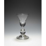 A heavy baluster glass, c.1710, the bell bowl with a solid base over a true baluster stem and