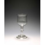 A large wine glass or goblet, c.1740, the deep tulip bowl raised on a plain stem with a central knop