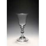 A large baluster glass goblet, c.1720-30, the generous round funnel bowl with an everted rim, raised