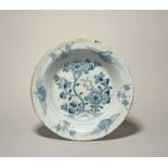 A large Liverpool delftware soup plate, mid 18th century, the well painted in blue with flowering