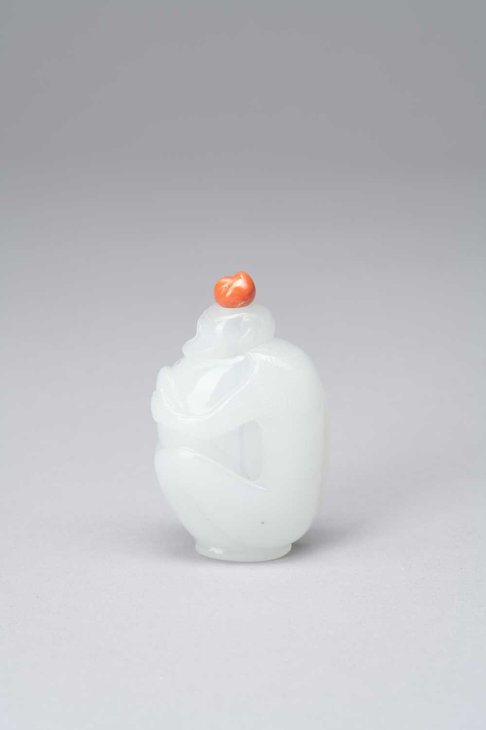 A CHINESE OPALESCENT WHITE GLASS SNUFF BOTTLE 1800-50Carved as a monkey clutching a large peach, the