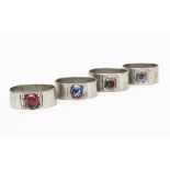 Four pewter and enamel napkin rings, each elliptical, hammered form with coloured enamel panel,