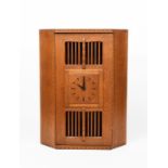 A Stanley Webb Davies oak corner cabinet with clock by Bob Willett, dated 1934, angled form, the