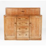 A Heal & Son limed oak sideboard, with central bank of four drawers, flanked by hinged single door