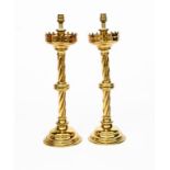 A pair of Reformed Gothic brass candlesticks, stepped domed bases supporting knopped, twisted