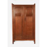 A Heal & Son fumed oak two door wardrobe, on four square section feet, panelled, hinged doors,