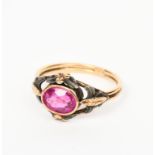 A gold and synthetic ruby ring, the openwork shoulder with foliate panels in silver and gilt, set