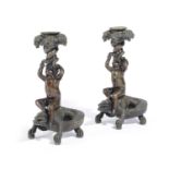 A PAIR OF FRENCH BRONZE CANDLESTICKS 19TH CENTURY each modelled as a cherub holding up a grape