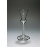 An unusual wine glass, c.1750, the thistle-shaped bowl with a hollow base, raised on a multi-