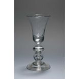A small baluster wine glass, c.1720, the bell bowl with a solid base enclosing a small tear,