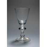 A heavy baluster wine glass, c.1720, the round funnel bowl with a solid base, the stem with an