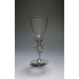 A Venetian or façon de Venise winged wine glass or goblet, 17th century, the rounded funnel bowl