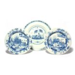 A pair of Dublin delftware large plates, c.1760, painted with small huts behind trees and cannon