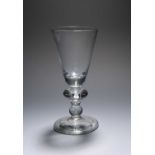 A large heavy baluster glass, c.1720, the generous round funnel bowl with a solid base, raised on an