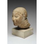 A Greek Archaic style marble head of a kouros with large almond shape eyes, straight nose and pursed