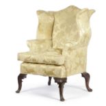 A MAHOGANY WING ARMCHAIR IN GEORGE II STYLE, LATE 19TH / EARLY 20TH CENTURY with a scroll back and