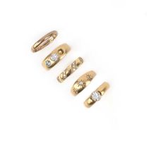 A group of five rings, comprising: a diamond solitaire on a yellow gold band, size J, British