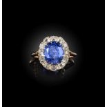 A sapphire and diamond ring, early 20th century, of cluster design, set with an oval sapphire