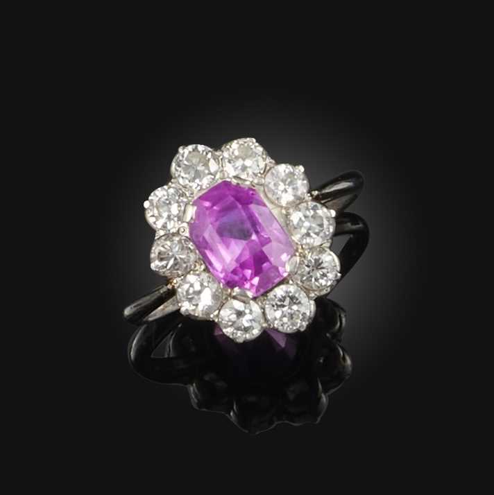 A pink sapphire and diamond ring, mid 20th century, of cluster design, set with an elongated
