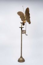 A KOREAN BRASS CANDLESTICK WITH BUTTERFLY 20TH CENTURY The tall stem raised on a stepped base and