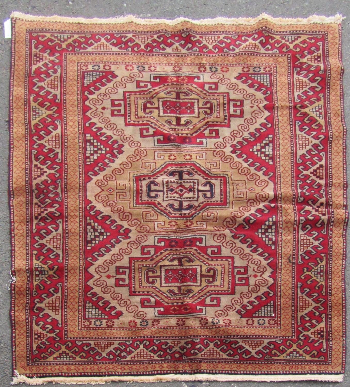 A Turkish Kazak Rug, with three hooked central medallions on a light brown field 189cm x 127cm,