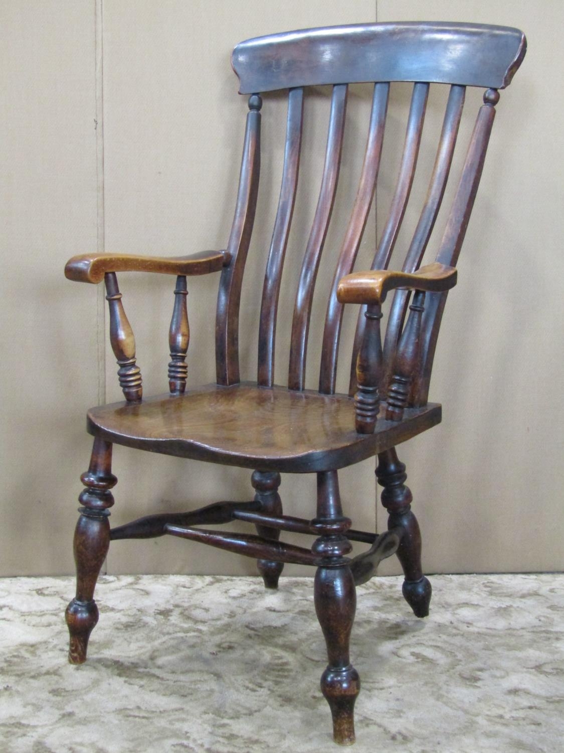 A Windsor stained elm and beechwood lathe back armchair raised on turned supports and stretchers