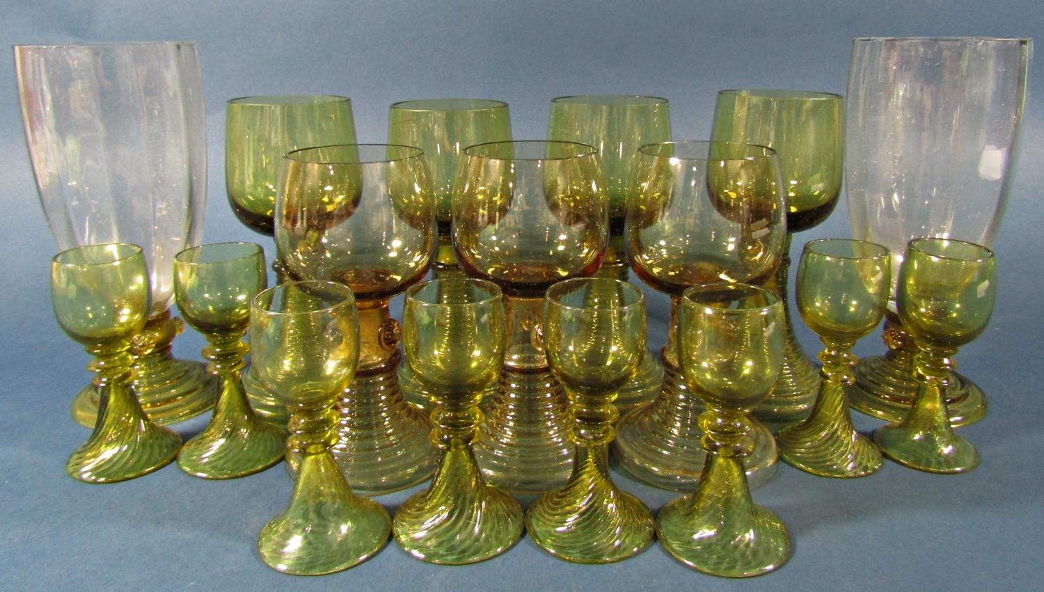 Fifteen near matching pale olive green spiral beehive wine glasses of varying sizes, and two similar