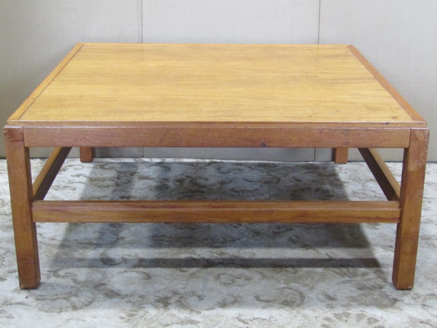 A low teak occasional table raised on square cut supports united by moulded stretchers,