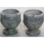A pair of small weathered circular garden urns with classical Greek key fruiting vine and further