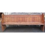 A pine church pew with planked seat and shaped chamfered ends approximately 7ft long