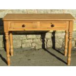 A Victorian style stripped pine side table fitted with two frieze drawers raised on turned tapered