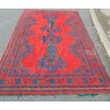 A large Turkey carpet with a central row of hooked medallion on a red ground, 280cm x 18cm