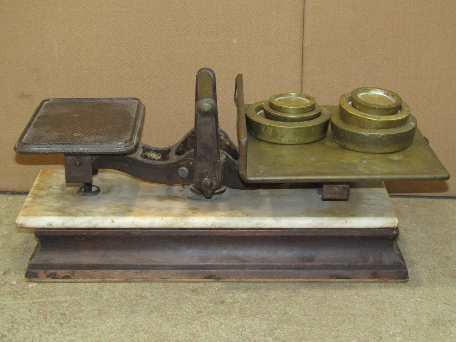A set of antique scales in cast iron and brass, raised on a marble platform and wooden base