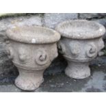 A pair of small weathered cast composition stone circular garden urns with repeating fixed ring